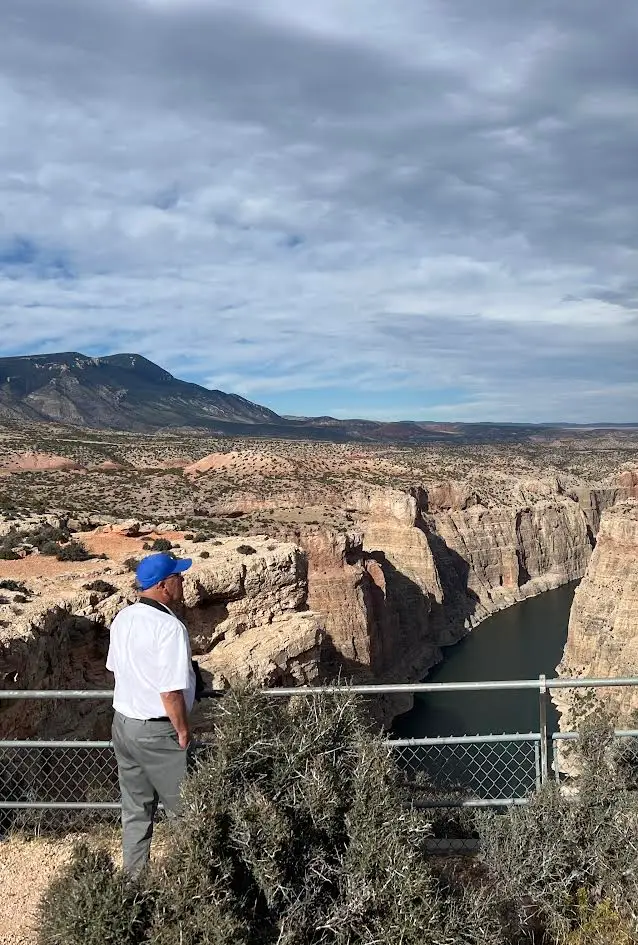 A person standing at Devil Canyon Overlook on a partly cloudy day.